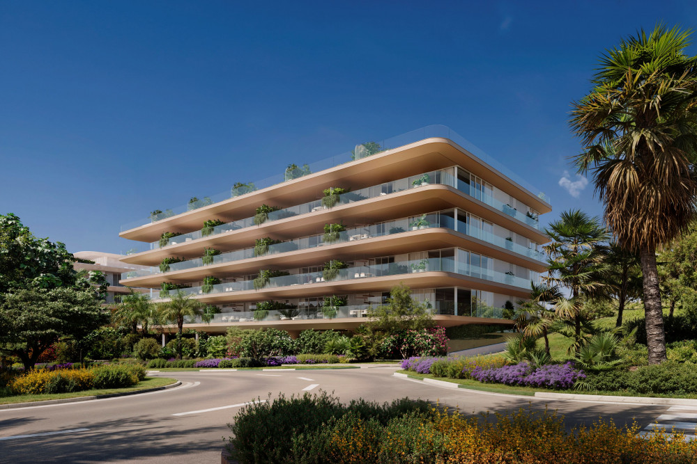 Modern apartment complex in Estepona, Málaga, featuring lush landscaping and large glass balconies.