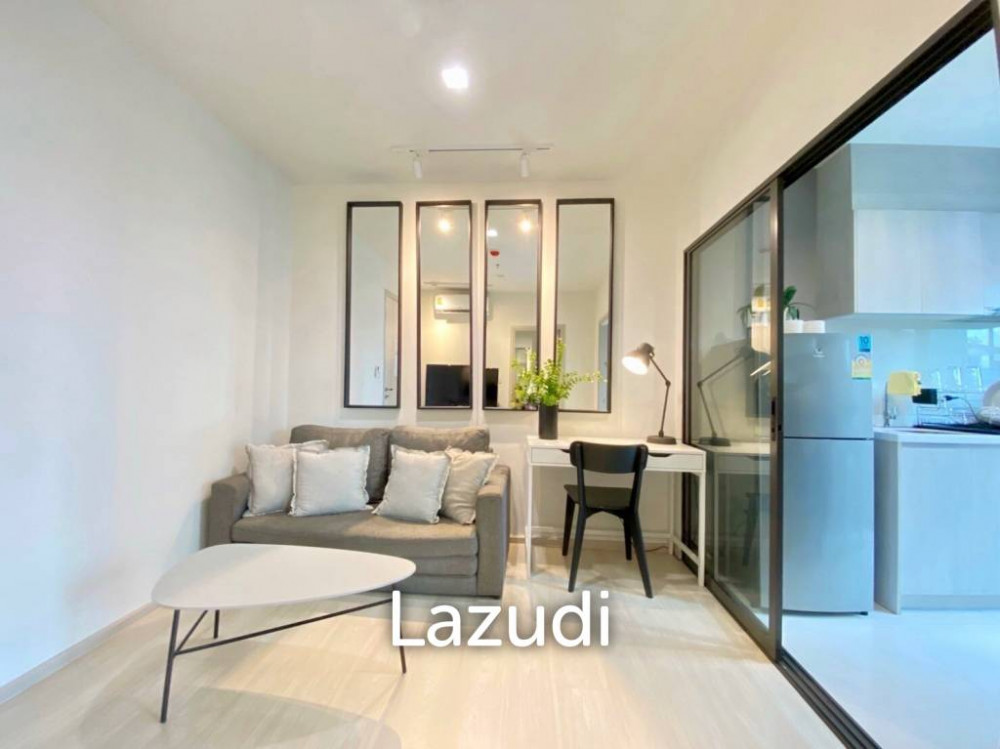 Cozy living area with modern furnishings, large mirrors, and a workspace near the kitchen in a contemporary apartment.